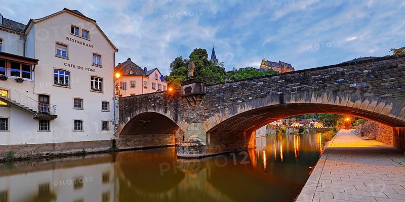 Town view of Vianden with the old stone bridge over the river Our and the castle in the evening, Grand Duchy of Luxembourg