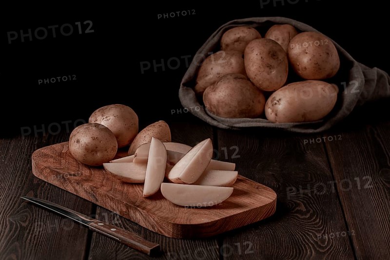 Raw potatoes, sliced, on a wooden table, top view, no people