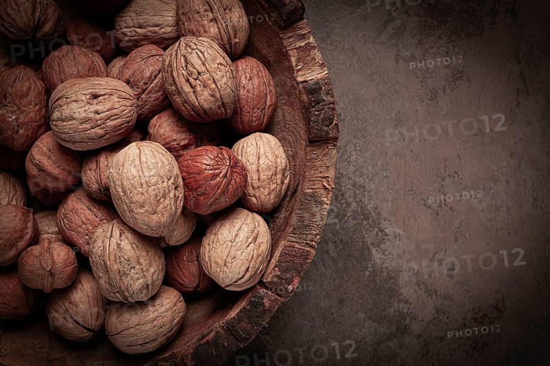 Fresh walnut in a shell, wooden plate, top view, no people