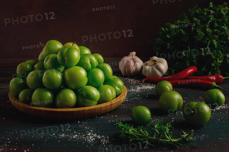 Tkemali, green cherry plum, with ingredients for sauce, cilantro, mint, hot pepper, garlic, on a wooden table, close-up, rustic, food background, no people, selective focus