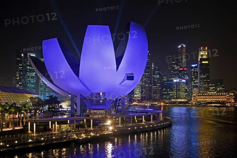 The purple illuminated ArtScience Museum and skyline with skyscrapers and high-rise buildings in Singapore at night