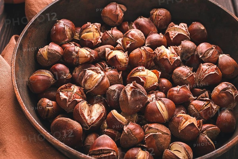 Roasted chestnuts, in an iron pan, wooden table, top view, no people, rustic style