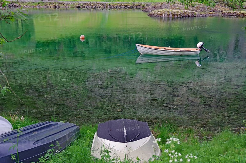 A small boat floats on a calm green lake, surrounded by grass and nature, Mindresundet, Stryn, norway
