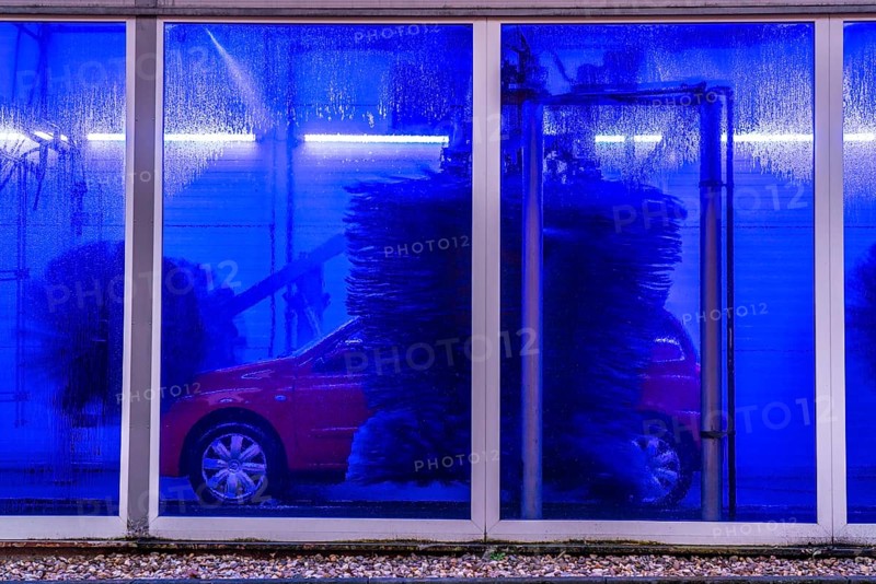 Car in an automatic car wash, car wash tunnel, cleaning foam is sprayed on, rotating brushes clean the vehicle