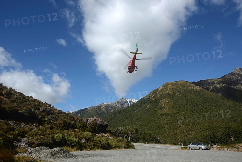 ARTHURS PASS, NEW ZEALAND, 2021-01-29: A brightly painted helicopter takes off from a car park in Arthur's Pass National Park, New Zealand, Oceania