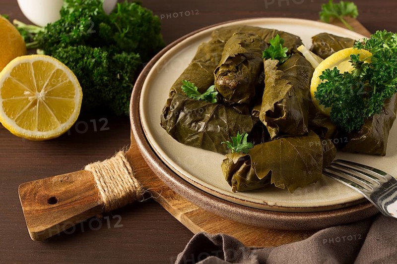 Dolma, cabbage rolls, grape leaves with filling, white sauce, lemon and herbs, rustic, selective focus, no people