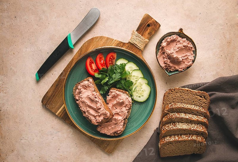 Liver meat pate spread on rye bread, breakfast, close-up, beige background. no people, selective focus