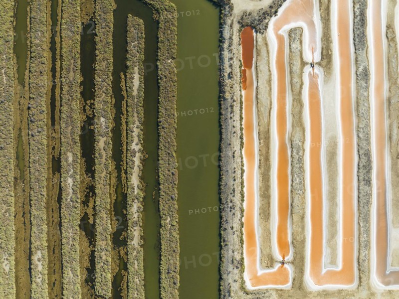 Saline ponds at the salt works near Chiclana de la Frontera. The orange-red colour depends on the level of salinity and is directly caused by the algae Dunaliella salina and brine shrimp. Aerial view. Drone shot. Cadiz province, Andalusia, Spain, Europe