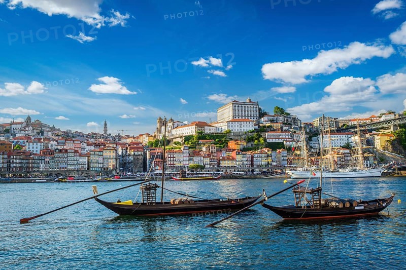 View of Porto city and Douro river with traditional boats with port wine barrels and sailing ship from famous tourist viewpoint Marginal de Gaia riverfront. Porto, Vila Nova de Gaia, Portugal, Europe
