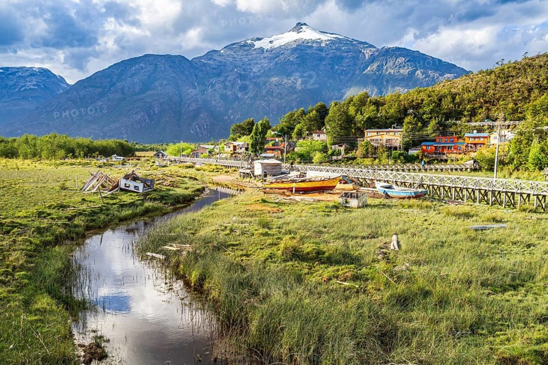 View over swampy meadows, houses and wooden boardwalk of Caleta Tortel, mountains in the back, Aysen region, Patagonia, Chile, South America