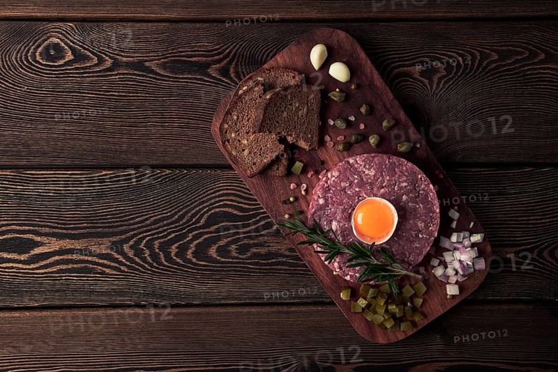 Beef tartare, with egg, capers, gherkins and bread, toned, top view, close up, horizontal, no people