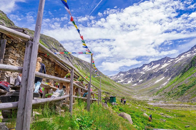 Scenery with a mountain farm, colourful flags and a path through the green mountain landscape under a cloudy sky, Klein Tibet, Zillertal, Austria, Europe