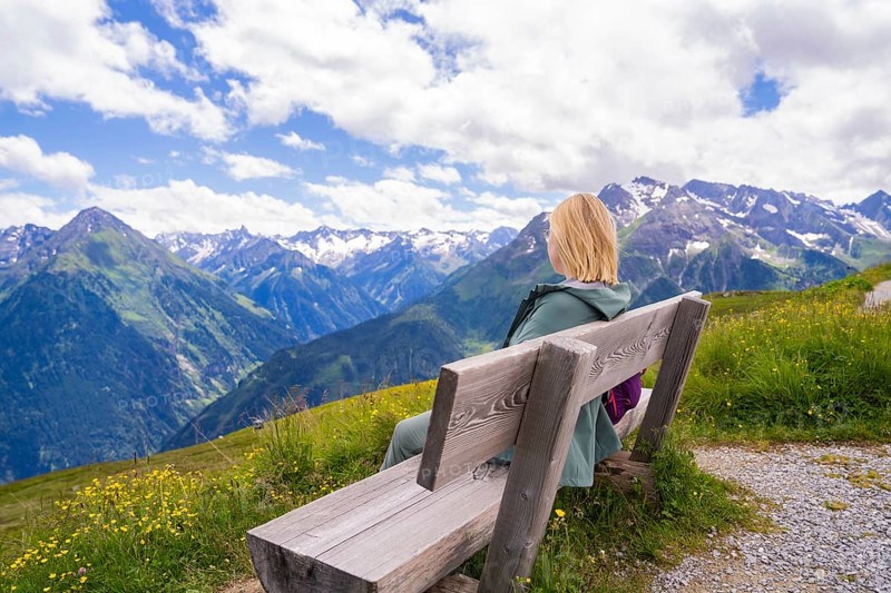 Woman sitting on a bench and enjoying the view of the mountain landscape under a clear sky, Penken, Zillertal, Austria, Europe