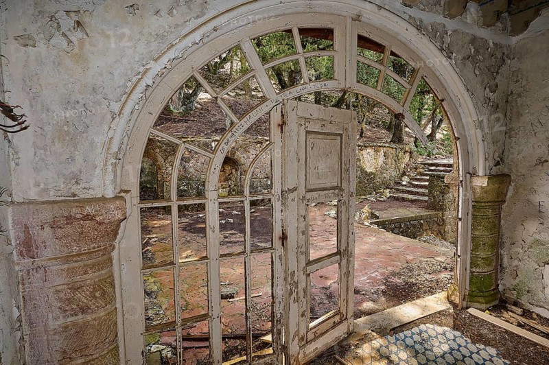 An abandoned building with an arched doorway, broken window panes and broken stone steps, conveying a gloomy and ruinous ambience, Mussolini Villa, Villa de Vecchi, Profitis Ilias, Empona, Rhodes, Dodecanese, Greek Islands, Greece, Europe