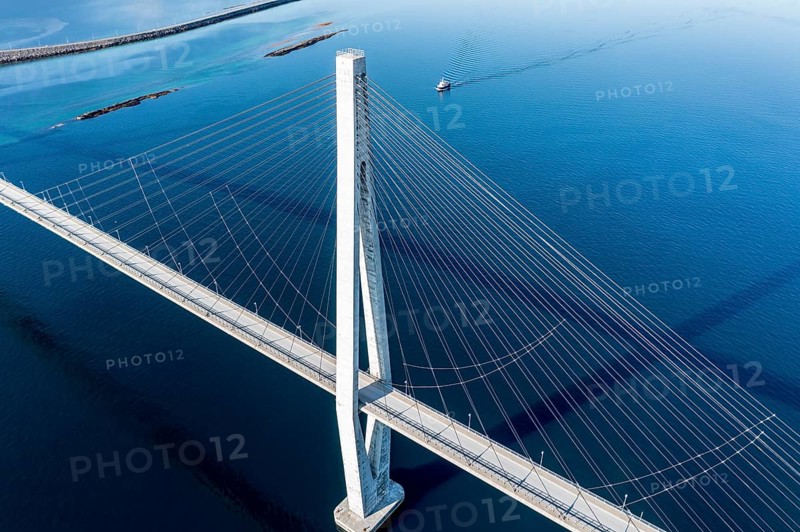 Aerial view of Helgeland bridge, connecting Sandnessjoen with the norwegian mainland, fishing boat passing by, Norway, Europe