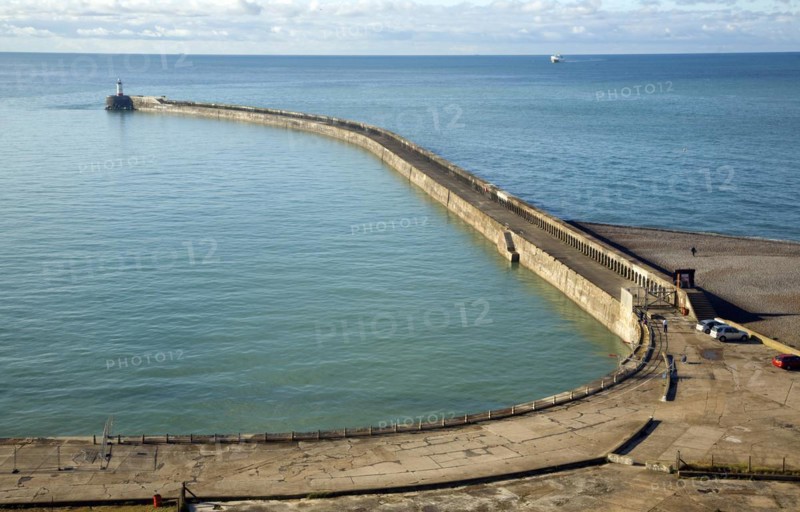 Large breakwater concrete groyne Newhaven, East Sussex, England. Sediment accumulation illustrates longshore drift