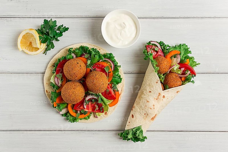Tortillas, wrapped falafel balls, with fresh vegetables, vegetarian healthy food, on a wooden white background, no people, selective focus