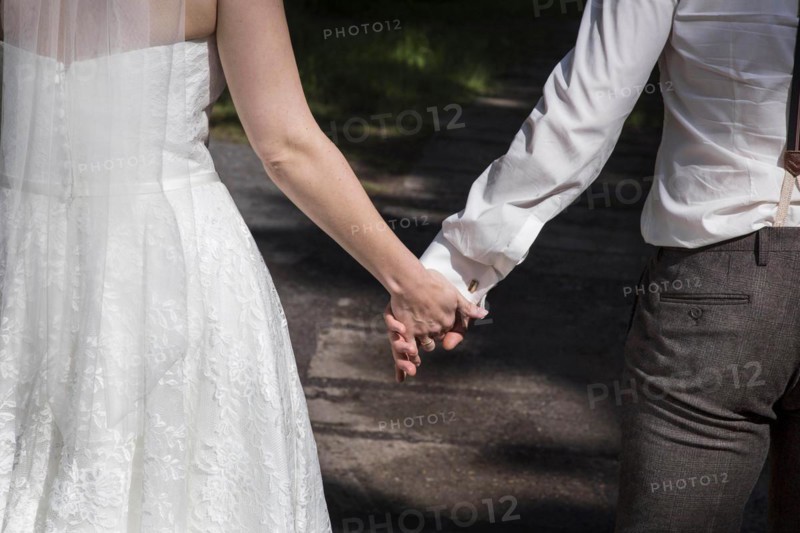 A bride and groom walk hand in hand to their church wedding on 14 June 2016