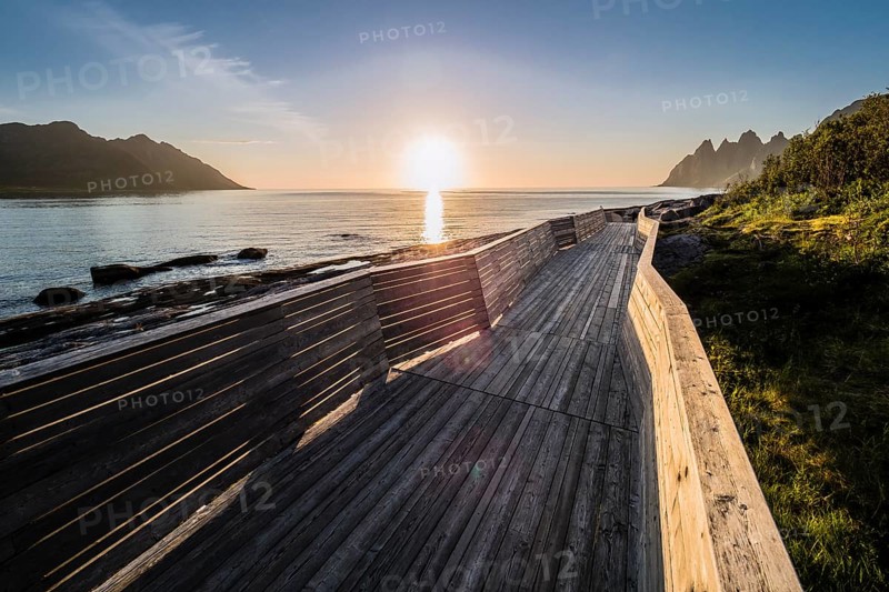 Coast at Tungeneset, sunset over the fjord, wooden path, view over rock formation to mountain range Okshornan, island Senja, Troms, northern Norway, Norway, Europe