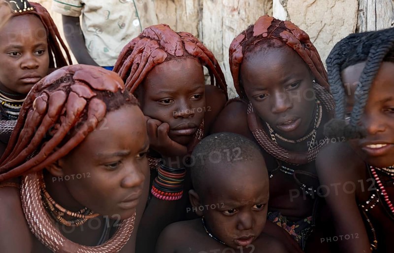 Group of Himba children and young woman look at pictures on a camera, near Opuwo, Kaokoveld, Kunene, Namibia, Africa