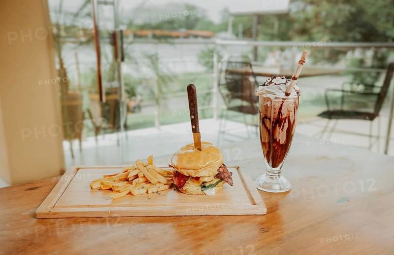 Classic burger with fries and milkshake on wooden board with copy space. Big hamburger with fries and milkshake on restaurant table