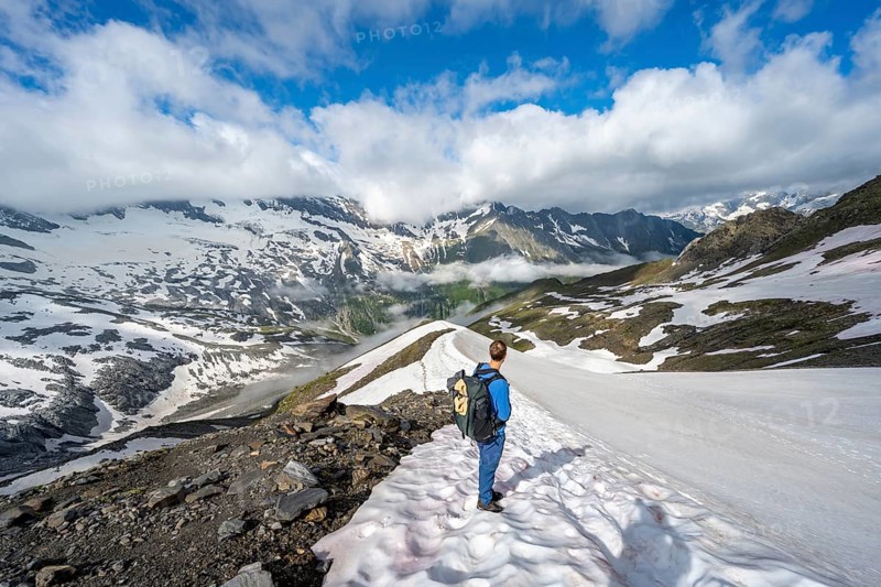 Mountaineer on hiking trail with snow, mountain landscape with summit Hoher WeiÃŸzint and Hochsteller with glacier Schlegeiskees, Berliner Höhenweg, Zillertal Alps, Tyrol, Austria, Europe