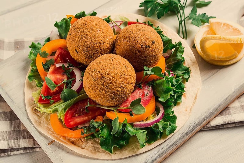 Tortillas, wrapped falafel balls, with fresh vegetables, vegetarian healthy food, on a wooden white background, no people, selective focus