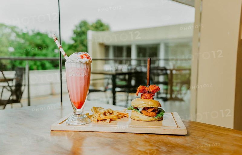 Traditional chicken burger with french fries and strawberry milkshake on restaurant table. Hamburger with french fries and strawberry milkshake on wooden table isolated