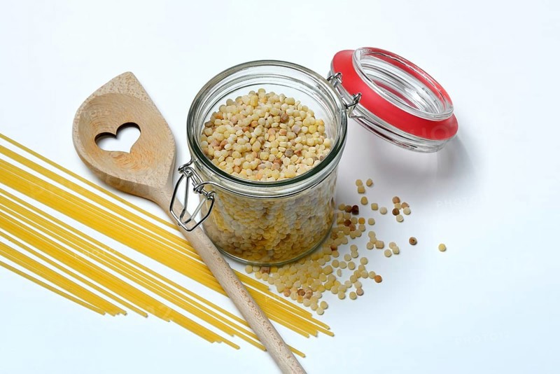 Fregola in wooden spoon and glass container with spaghetti, pasta variety from Sardinia, Italy, Europe