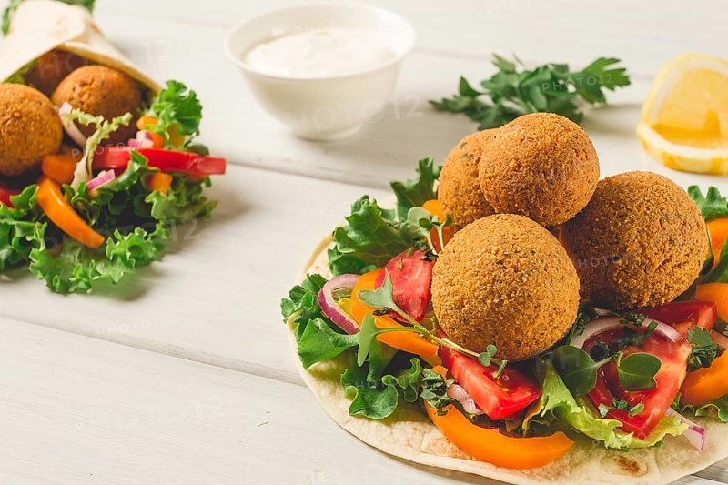 Tortillas, wrapped falafel balls, with fresh vegetables, vegetarian healthy food, on a wooden white background, no people, selective focus