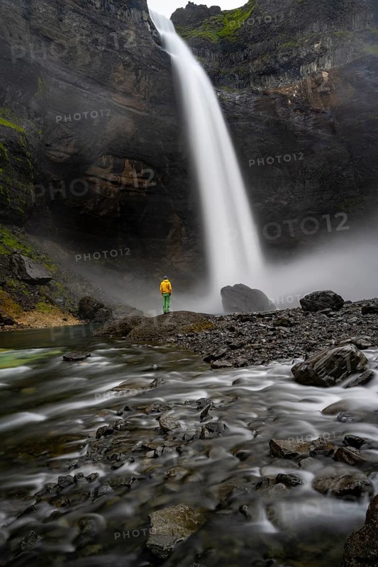 Young man with yellow jacket standing in front of waterfall, Haifoss and Granni waterfall at a canyon, Fossa Ã­ Îjorsardal, with river Ã­ Îjorsardal, long exposure, dramatic landscape, Hekla, Iceland, Europe