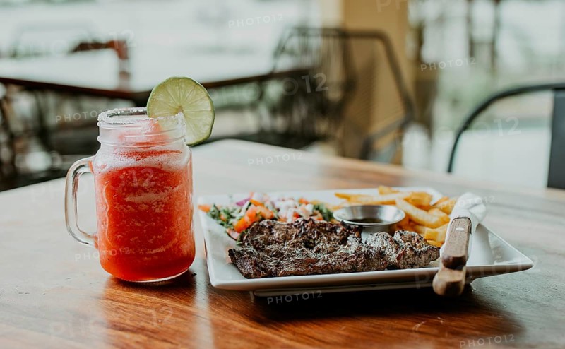 Delicious homemade steak with fries and strawberry lemonade. Nicaraguan skirt steak with fries and drink served on wooden table