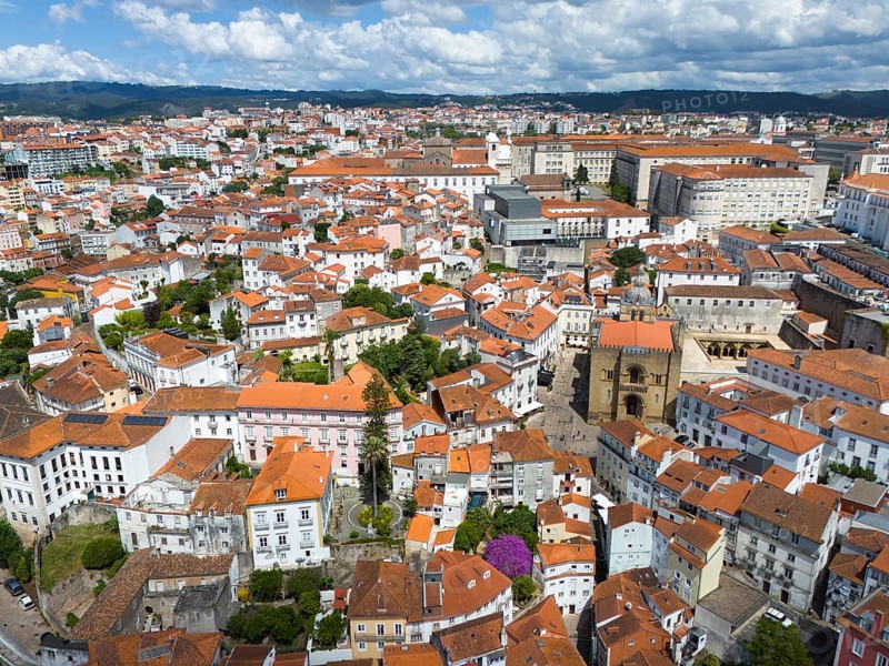 Dense urban environment with old red tiled roofs and historic architecture under a cloudy sky, aerial view, Coimbra, Rio Mondego, Portugal, Europe