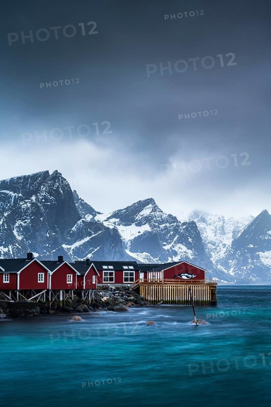 Rorbuer cabins of Hamnoy by the fjord, snowy mountains in the back, Hamnoy, Reine, Moskenesoya, Lofoten, Norway, Europe