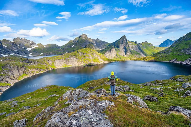 Mountaineer looking over lake, mountain landscape with lake Tennesvatnet, at sunrise, behind peak of Hermannsdalstinden, Moskenesoya, Lofoten, Nordland, Norway, Europe