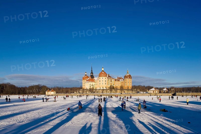 Moritzburg, castle park in winter with ice skaters on the frozen castle pond