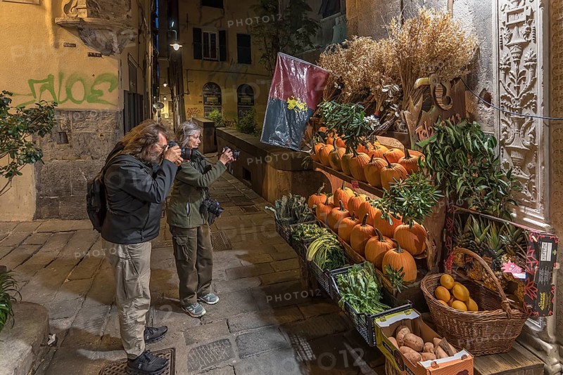 Tourists photographing a fruit shop in the evening in the historic centre, Genoa, Italy, Europe