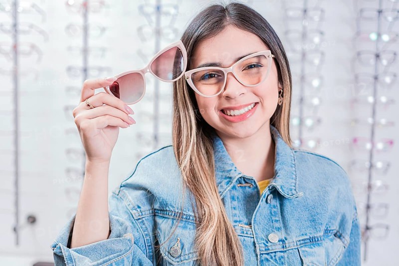 Smiling female customer trying on glasses in eye shop. Beautiful girl trying on glasses in an eye store