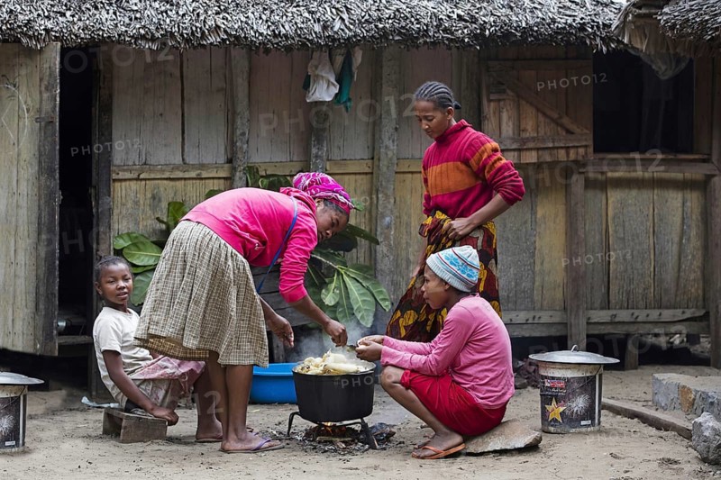 Malagasy family cooking maniok in front of traditional wooden house in rural village, Vatovavy-Fitovinany, Madagascar, Southeast Africa, Africa