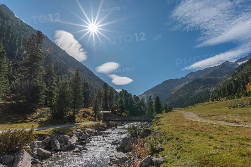 Wooden bridge over Zamser Bach in the valley Zamser Grund, Schlegeis, hiking trail, coniferous forest, rocks, backlight, blue sky, Zillertal Alps, Tyrol, Austria, Europe