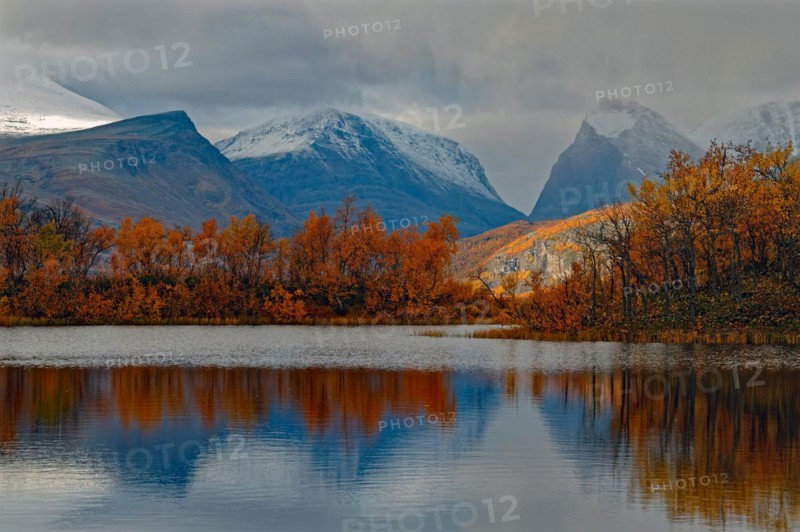Autumn atmosphere at a lake framed by birch trees, autumn, intense colours, reflections, in the background mountains Tuolpagorni on the right, mountain Singitjakka on the left, in the middle valley Singivagge, Nikkaluokta, Kiruna, GÃ¤llivare, Norrbottens lÃ¤n, Lapland, Northern Sweden, Sweden, Europe