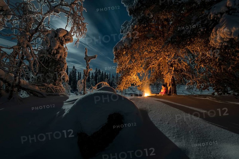 Man in the evening at a bivouac with campfire, Lapland, Sweden, Scandinavia, Europe