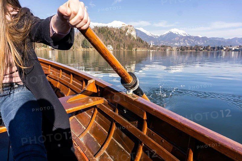 Young woman using paddle on a wooden boat, Lake Bled Slovenia rowing on wooden boats on a sunny day