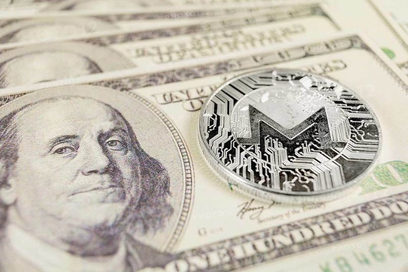MONERO XMR cryptocurrency, silver monero coin on the background of Dollar bills