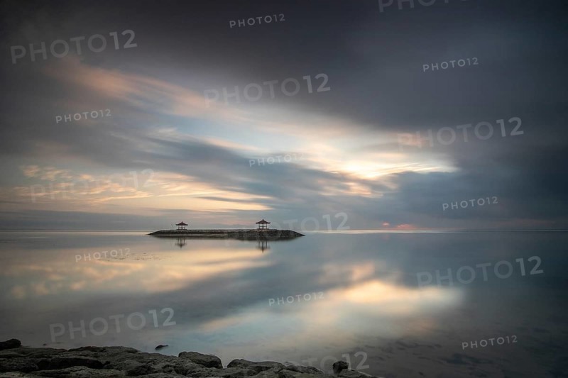 Beautiful seascape in the morning. Tropical sandy beach with breakwater and reflection of the sky in the calm water. Morning landscape, taken in Sanur, Bali, Indonesia, Asia