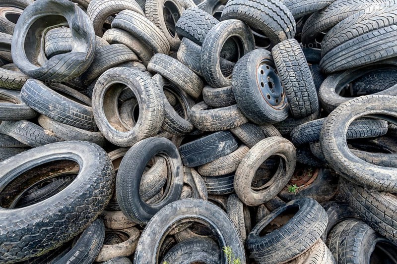 Old broken car tyres piled up up to form a mountain as a background