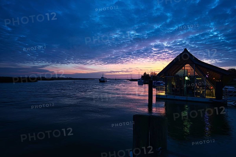 From the harbor in zingst the bodden view with burning sky with house. dynamic clouds in full color splendor