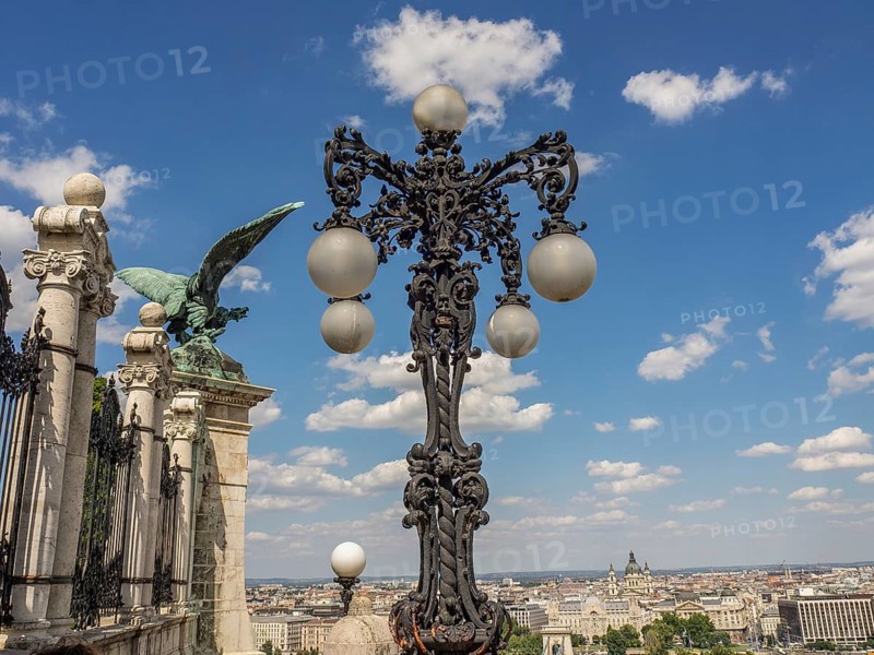 Artistic street lamp and green statue in front of a blue sky with clouds, budapest, danube, hungary