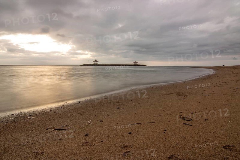 Beautiful seascape in the morning. Tropical sandy beach with breakwater and reflection of the sky in the calm water. Morning landscape, taken in Sanur, Bali, Indonesia, Asia