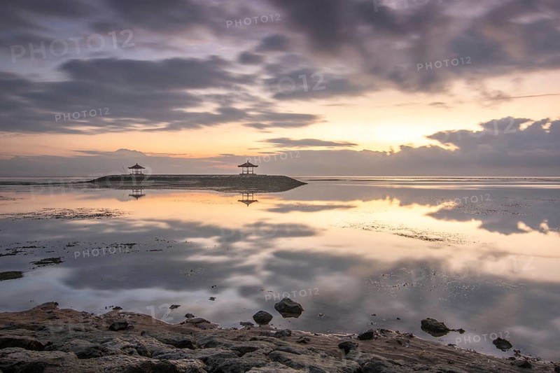 Beautiful seascape in the morning. Tropical sandy beach with breakwater and reflection of the sky in the calm water. Morning landscape, taken in Sanur, Bali, Indonesia, Asia
